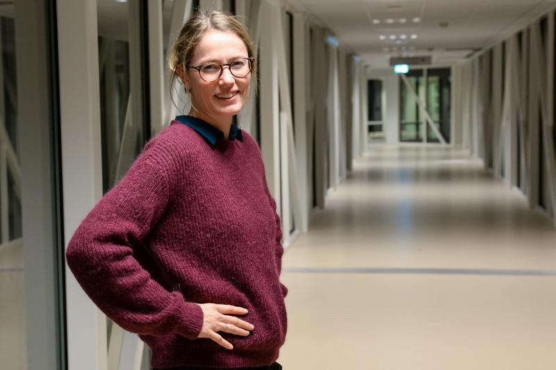 Ei kvinne i raud genser står i ein gang.